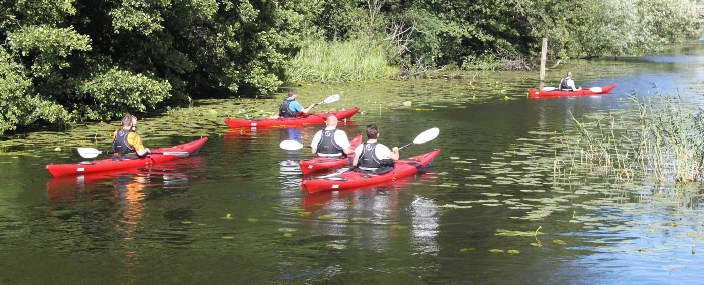 En grupp människor som paddlar kanot längs en kanal.