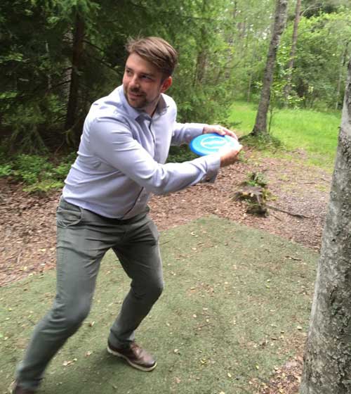 En person kastar en frisbeegolf i skogen.