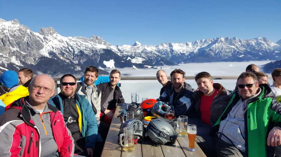 En grupp människor sitter med utsikt över Alperna.